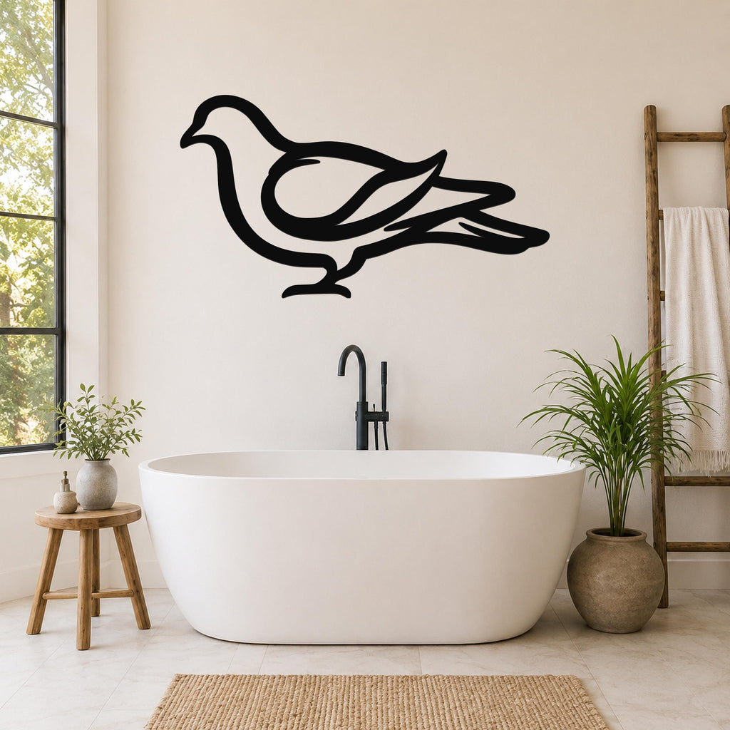 Black metal pigeon wall art silhouette mounted on a bathroom wall above a freestanding tub, with visible cutout details of the bird's wings and tail.