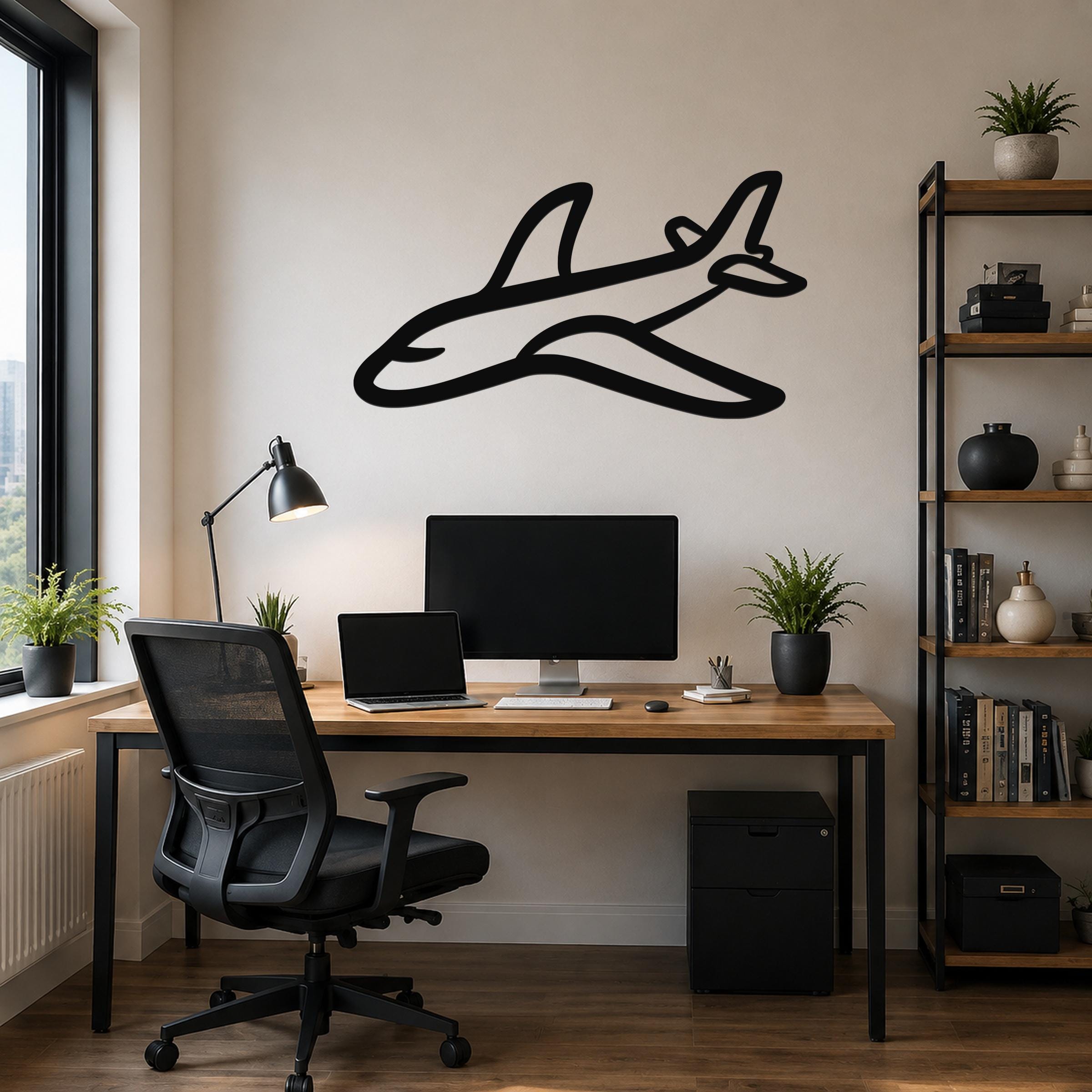 Black metal airplane wall art silhouette with internal cutout details, mounted above a wooden desk in a modern home office.