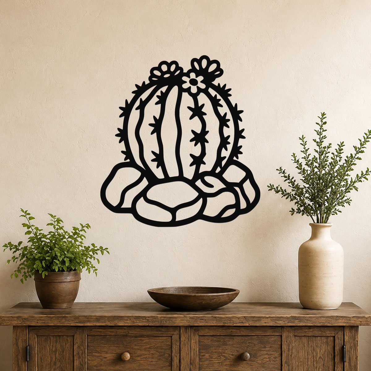 Black metal barrel cactus wall art with flower and spine cutouts, mounted on a beige wall above a wooden console table.