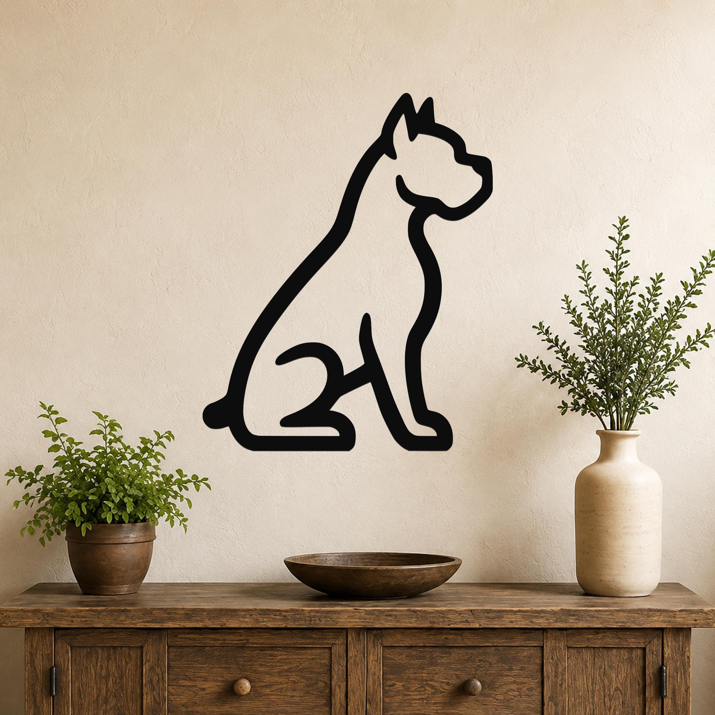 Black metal wall art of a sitting boxer dog silhouette, mounted on a beige wall above a wooden console table with potted plants.