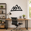 Black metal mountain silhouette wall art mounted above a wooden desk in a modern home office.