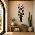 Black metal ocotillo wall art with branching cutouts, mounted on a beige wall above a wooden bench in a sunlit entryway.