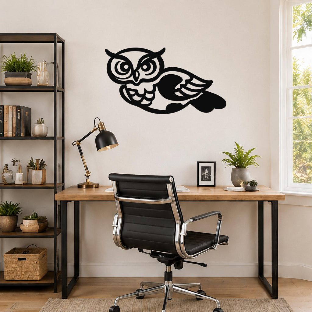Black metal owl wall art with cutout details, mounted above a wooden desk in a home office.
