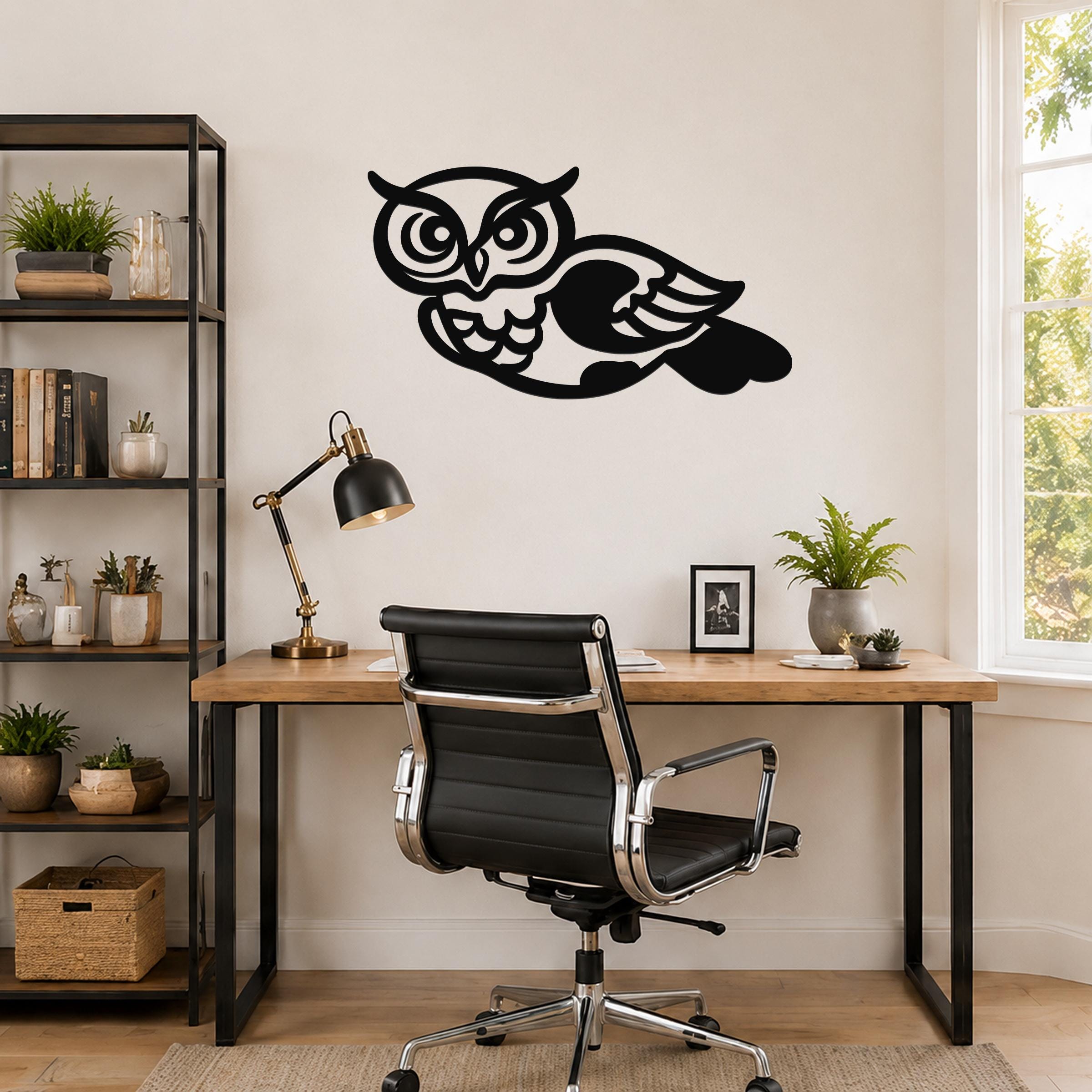 Black metal owl wall art with cutout details, mounted above a wooden desk in a home office.
