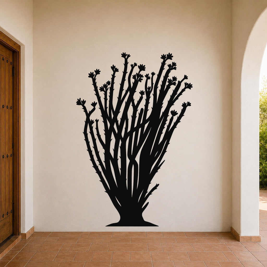 Black metal ocotillo wall art with branching stems and flower cutouts, mounted on a beige wall in a covered entryway with terracotta tile flooring.