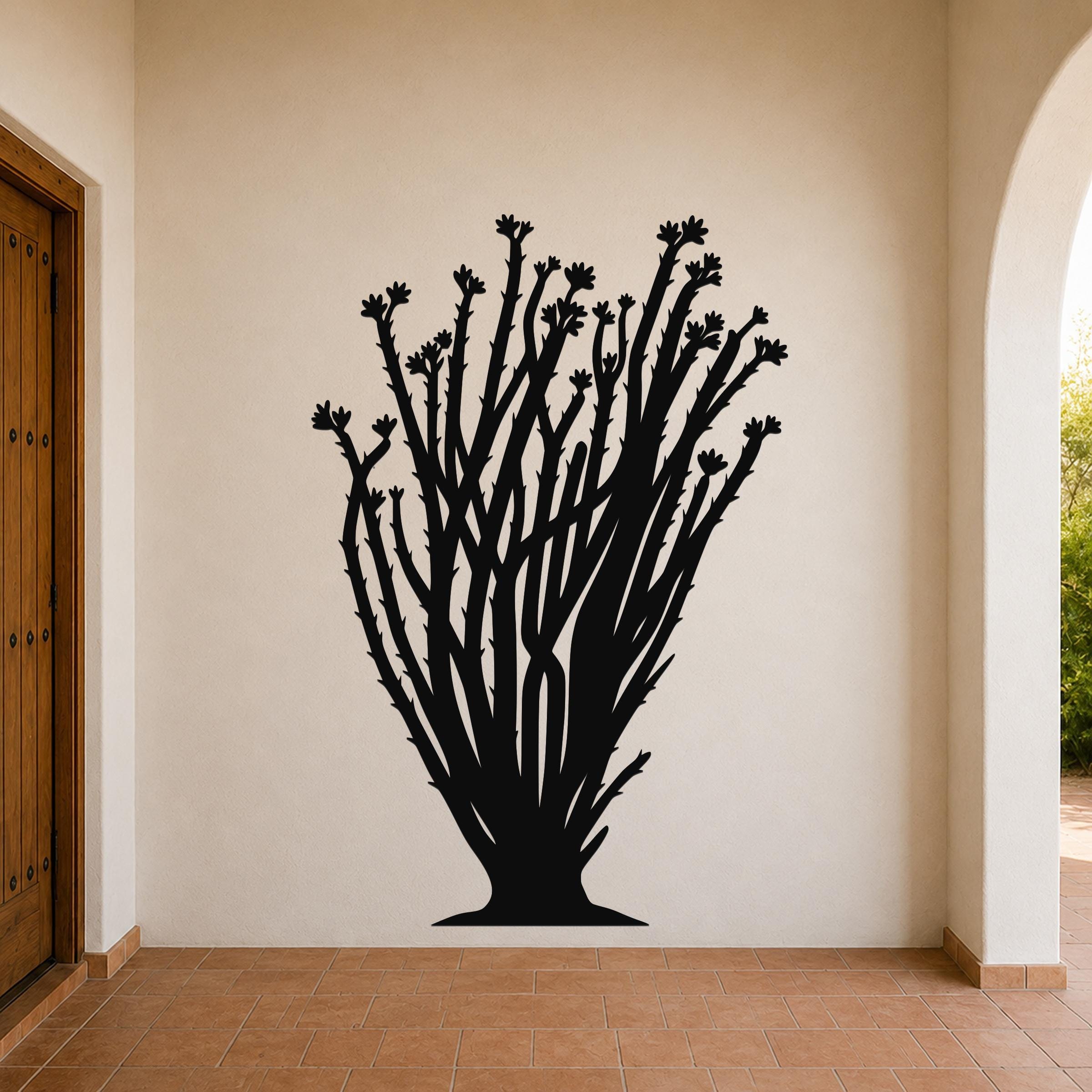 Black metal ocotillo wall art with branching stems and flower cutouts, mounted on a beige wall in a covered entryway with terracotta tile flooring.