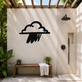 Black metal rain cloud wall art with raindrop cutouts, mounted on a beige outdoor shower wall above a wooden bench.