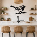 Black metal bird wall art silhouette perched on a branch, mounted above a kitchen counter with white marble and wooden shelves.