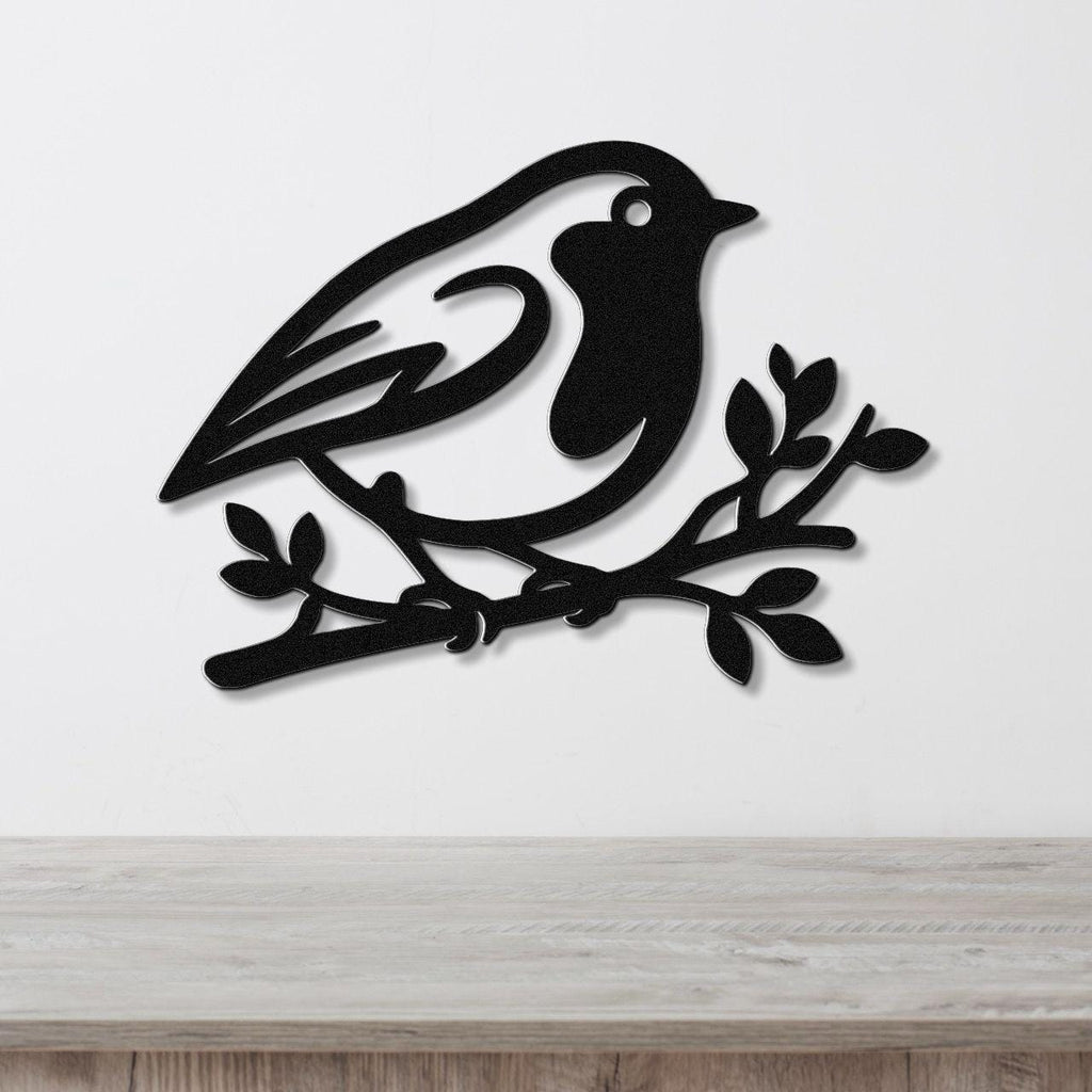 Black metal wall art featuring a robin silhouette perched on a branch, mounted on a white wall above a light wood surface.