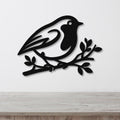 Black metal wall art featuring a robin silhouette perched on a branch, mounted on a white wall above a light wood surface.