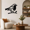 Black metal robin wall art silhouette perched on a branch, mounted on a living room wall above a white armchair.