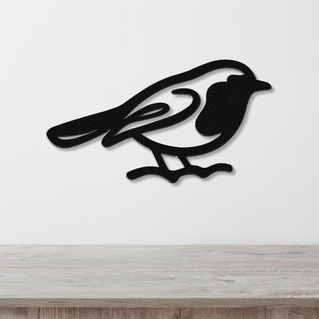 Black metal robin wall art silhouette with internal cutout details, mounted on a white wall above a light wood countertop.