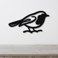 Black metal robin wall art silhouette with internal cutout details, mounted on a white wall above a light wood countertop.