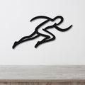 Black metal runner wall art with motion-line cutouts, mounted on a white wall above a light wood counter.
