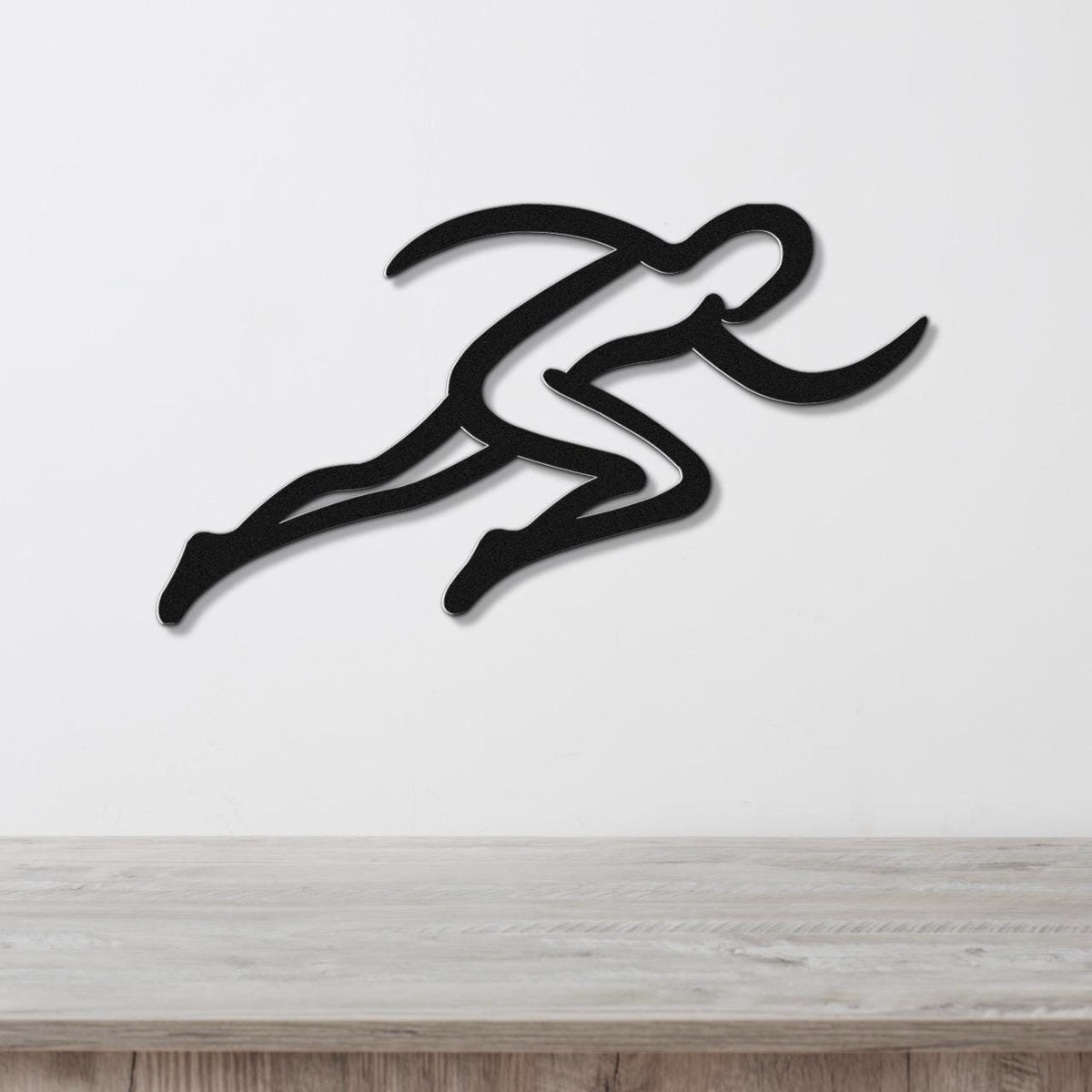 Black metal runner wall art with motion-line cutouts, mounted on a white wall above a light wood counter.