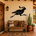 Black metal quail wall art with motion-line cutouts, mounted above a wooden bench on a stucco patio wall.