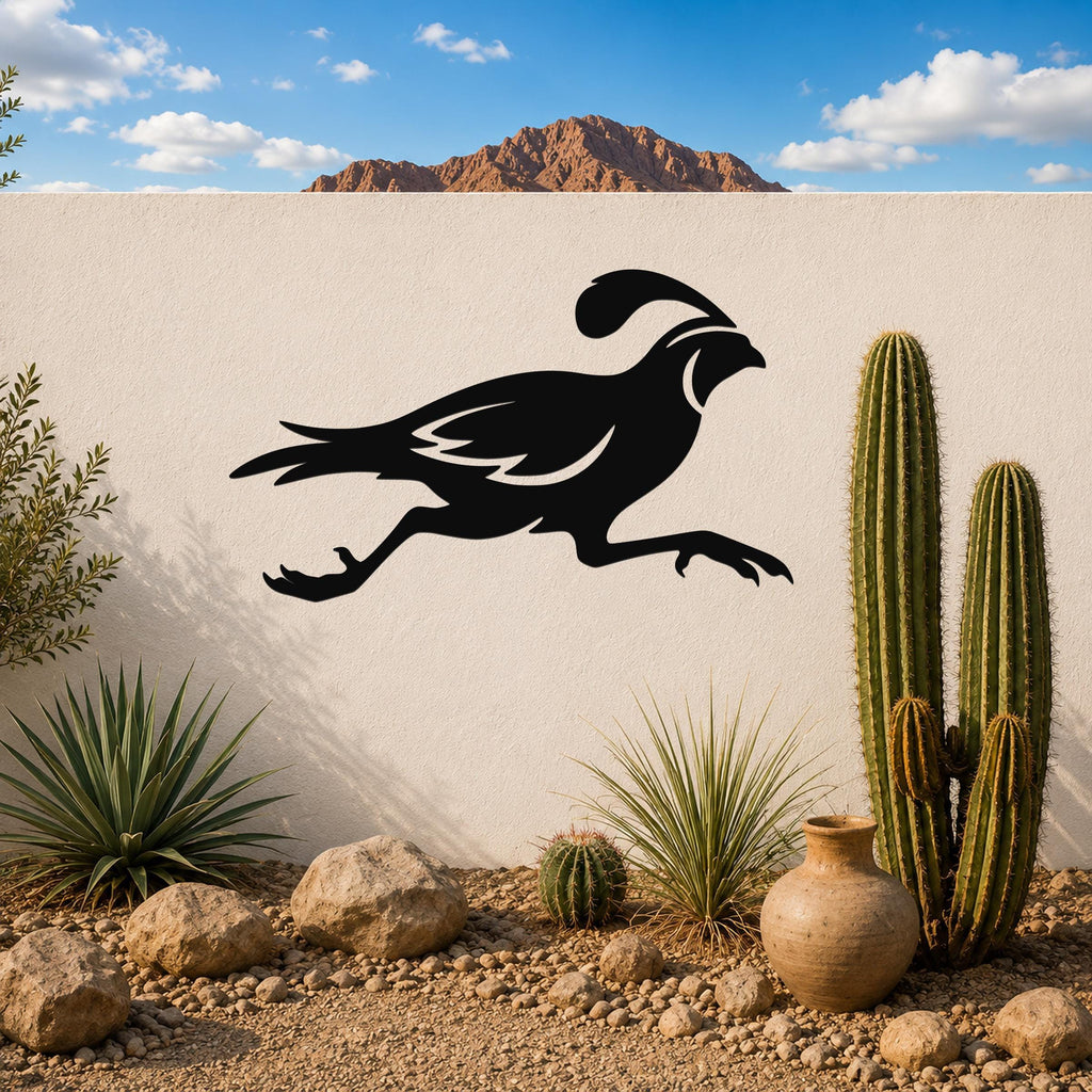 Black metal quail wall art in a running silhouette, mounted on a white outdoor wall above a desert garden with cacti and rocks.