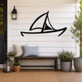Black metal sailboat wall art with a silhouette design, mounted on a white shiplap wall above a wooden bench in a coastal porch setting.