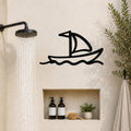 Black metal sailboat wall art with wave cutouts, mounted on a bathroom wall above a built-in shelf.