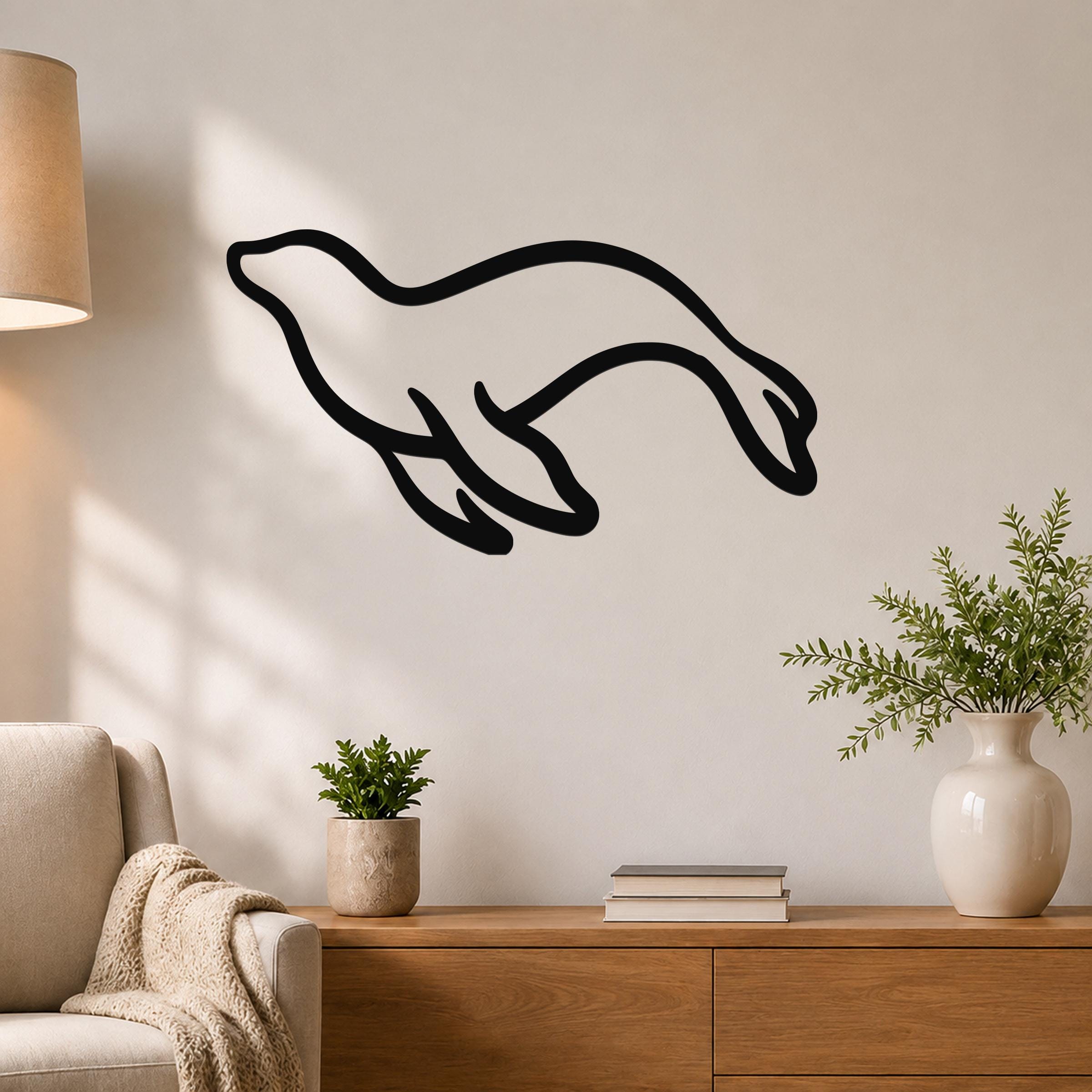 Black metal sea lion wall art with a flowing silhouette, mounted on a living room wall above a wooden console table.