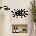 Black metal sea urchin wall art with spiky cutout design, mounted on a bathroom wall above a built-in shelf.