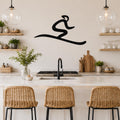 Black metal wall art in a flowing, abstract ski silhouette, mounted on a kitchen wall above a counter with wicker bar stools.