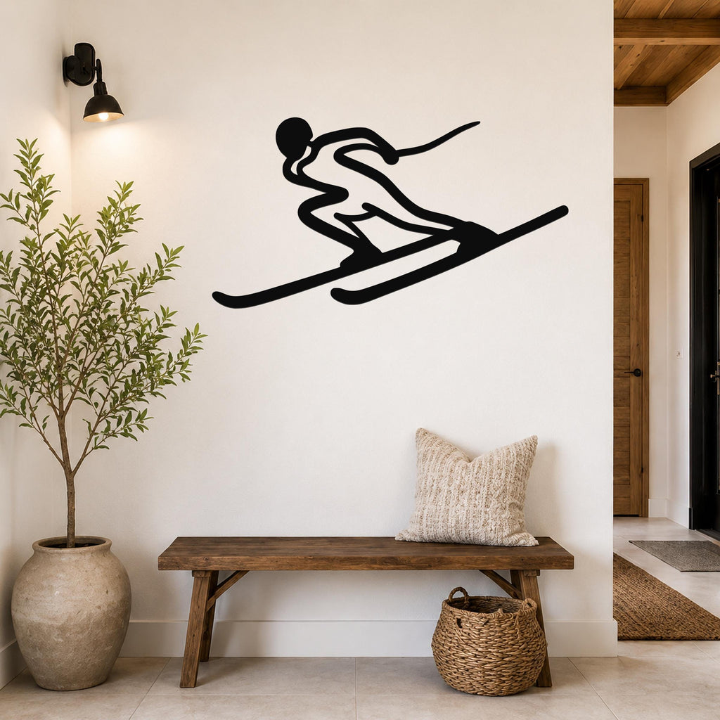 Black metal skier silhouette wall art with motion-line cutouts, mounted on a white wall above a wooden bench in a modern entryway.