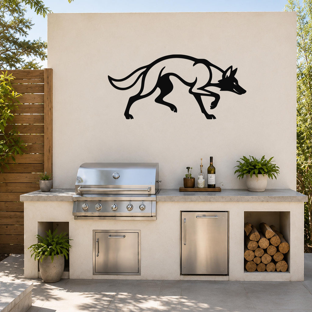 Black metal coyote wall art with motion-line cutouts, mounted on an outdoor kitchen wall above a stainless steel grill and counter.