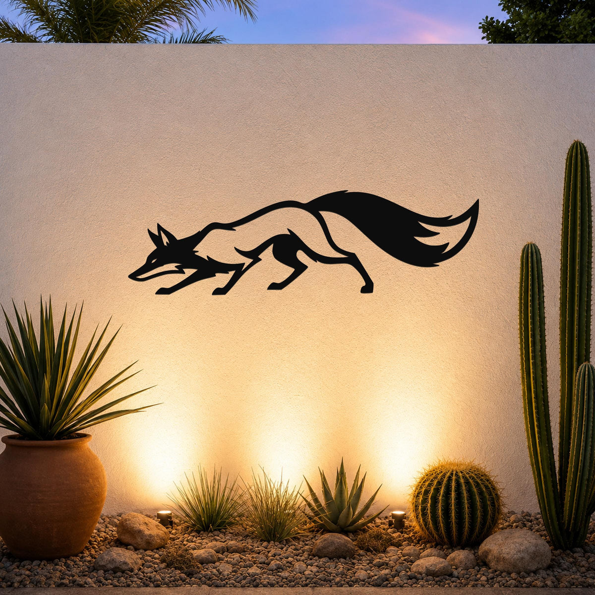 Black metal fox wall art with a silhouette cutout design, mounted on an outdoor wall above a desert garden with cacti and warm uplighting.