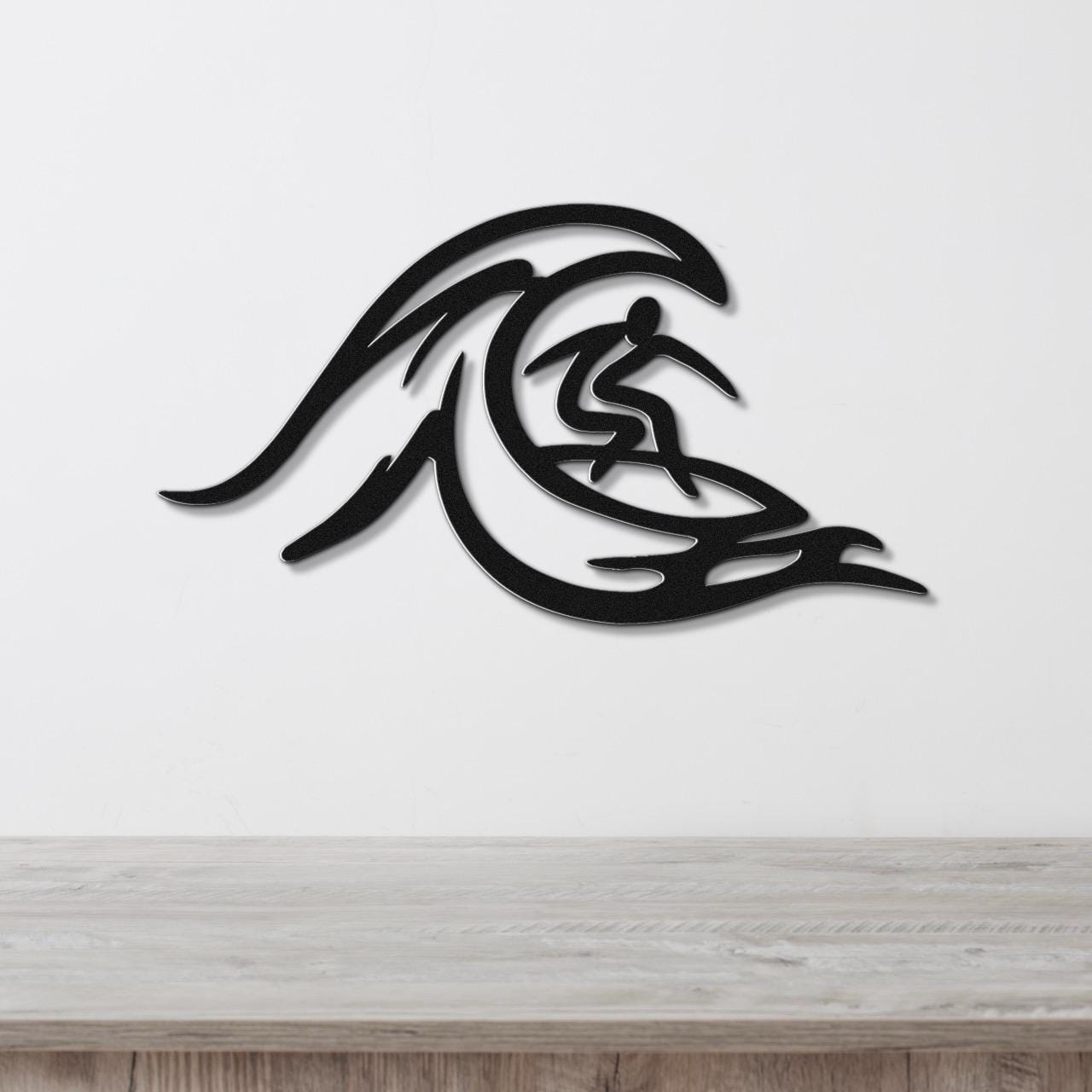 Black metal wall art featuring a surfer silhouette riding a wave, mounted on a white wall above a wooden surface.