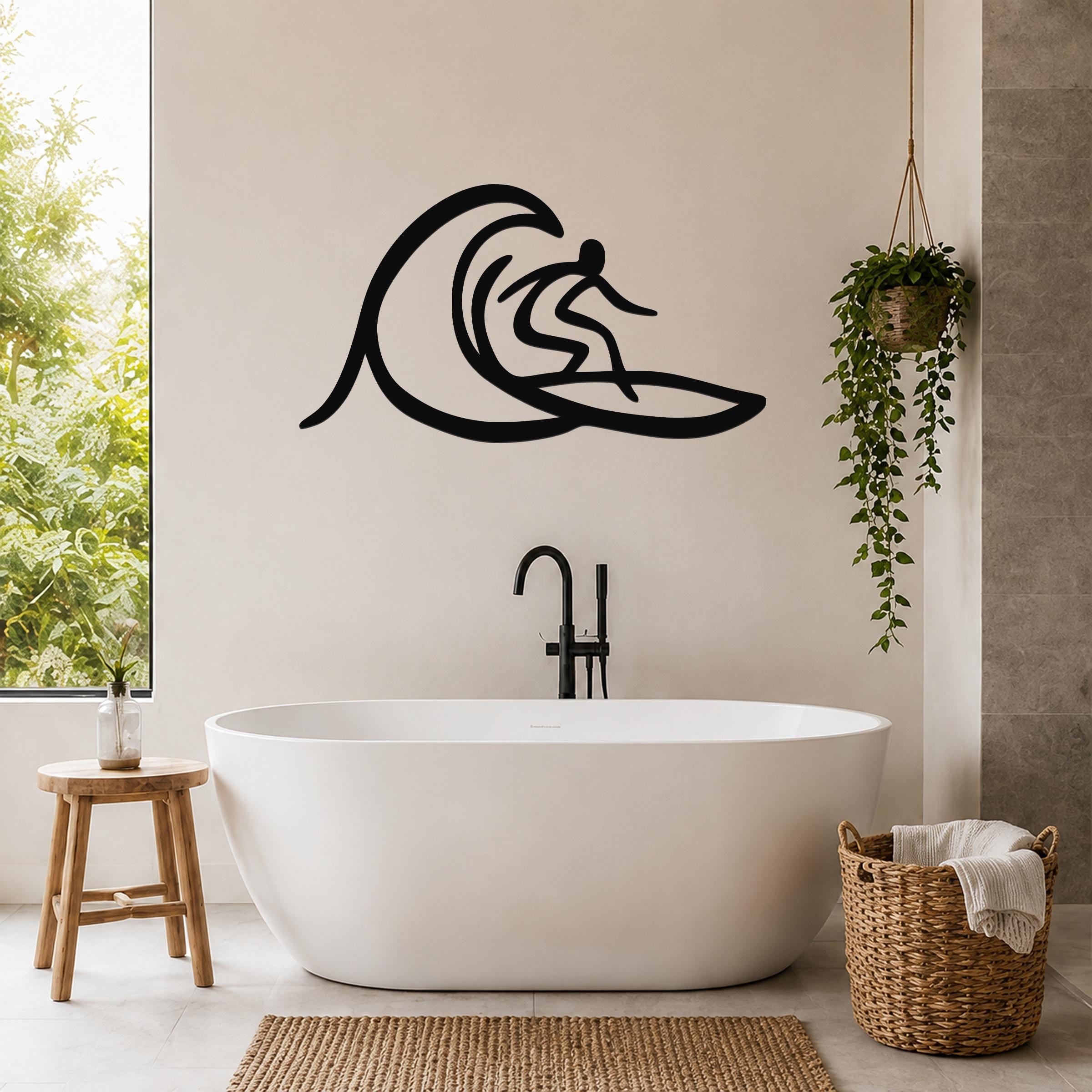 Black metal surfer wall art with wave silhouette, mounted on a bathroom wall above a freestanding tub.