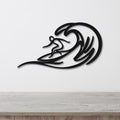 Black metal surfer wall art with wave cutouts, mounted on a white wall above a wooden counter.