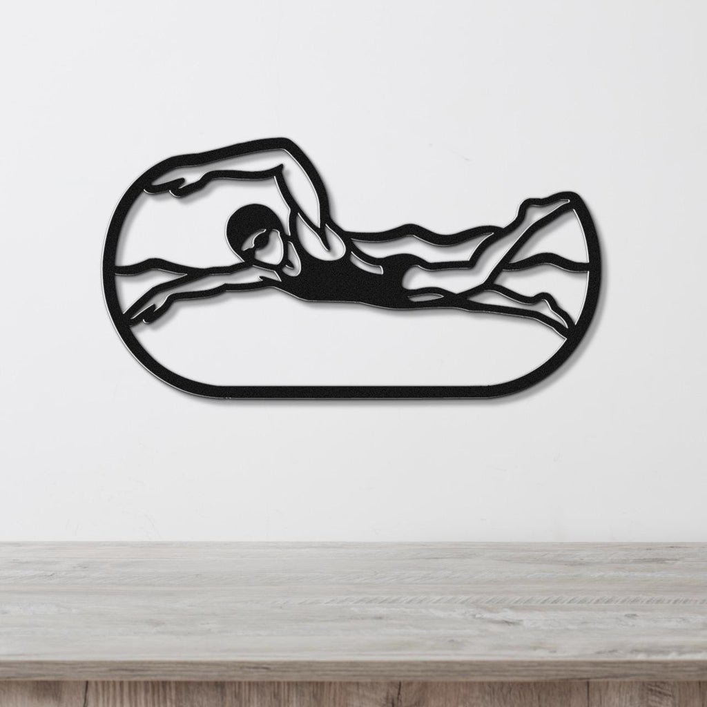 Black metal swimmer wall art with motion-line cutouts, mounted on a white wall above a light wood counter.