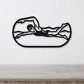 Black metal swimmer wall art with motion-line cutouts, mounted on a white wall above a light wood counter.