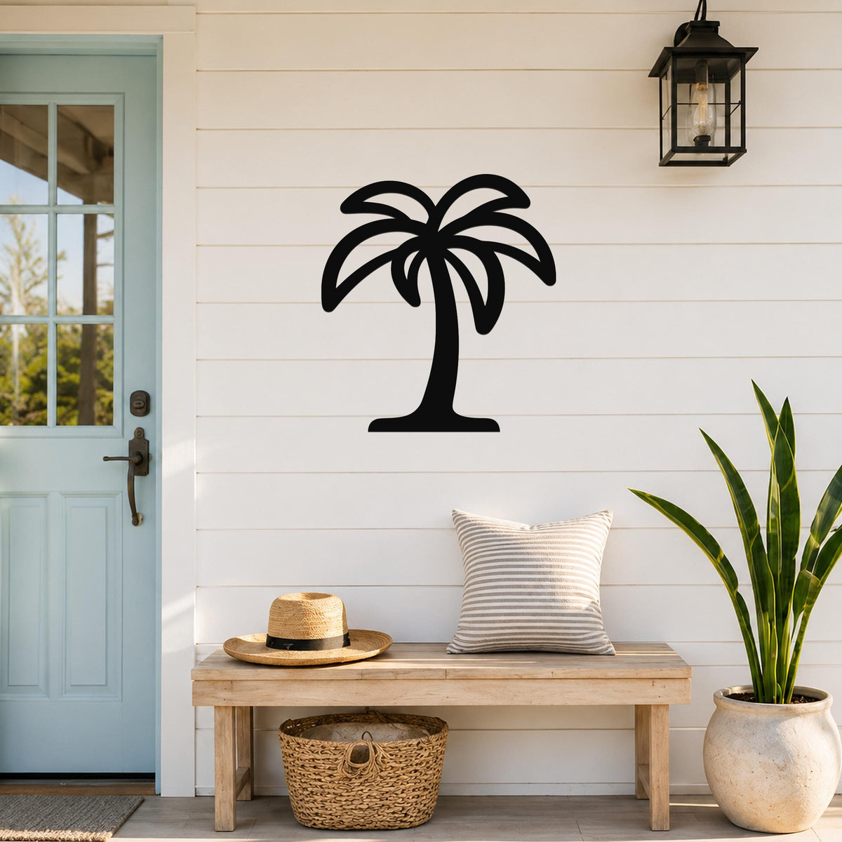 Black metal palm tree wall art with leaf cutouts, mounted on a white shiplap wall above a wooden bench in a coastal entryway.