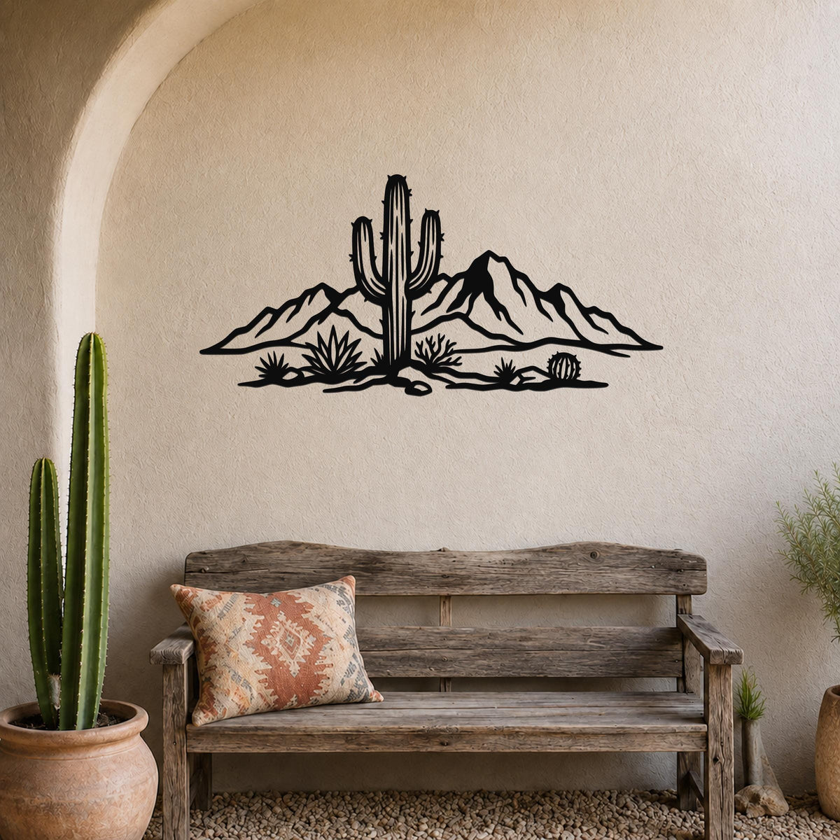 Black metal wall art silhouette of a saguaro cactus and desert mountains, mounted above a wooden bench in a rustic living space.