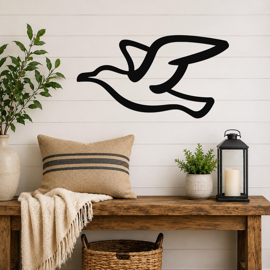 Black metal seagull wall art with motion-line cutouts, mounted above a wooden bench in a farmhouse-style entryway.