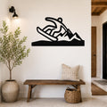 Black metal wall sculpture of a snowboarder in motion, mounted above a wooden bench in a modern entryway.