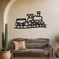 Black metal train wall art with a classic locomotive and car silhouette, mounted on a textured beige wall above a rustic wooden bench in a sunlit entryway.