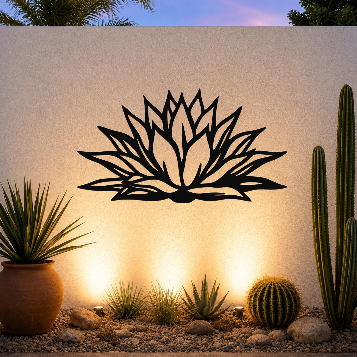 Black metal agave wall art with bold geometric cutouts, mounted on an outdoor wall above a desert garden with cacti and warm uplighting.