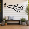Black metal airplane wall art with bold silhouette design, mounted on a white shiplap wall above a wooden bench on a porch.