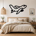 Black metal airplane wall art with a sleek silhouette design, mounted above a wooden bed in a neutral-toned bedroom.
