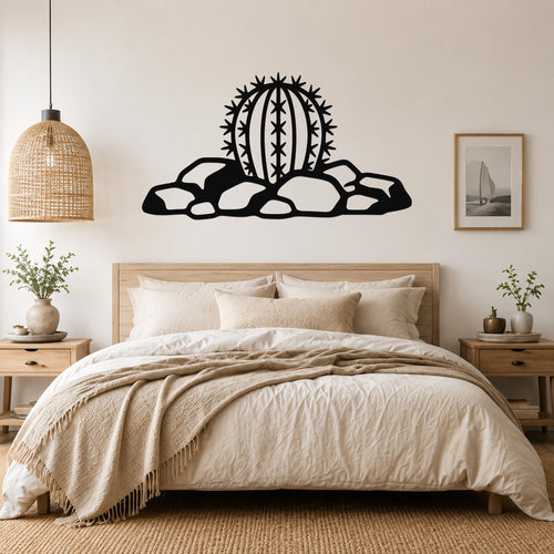 Black metal barrel cactus wall art with spines and rocks cutout, mounted above a bed in a neutral bedroom.