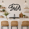 Black metal bear silhouette wall art with internal line details, mounted on a kitchen wall above a white countertop.