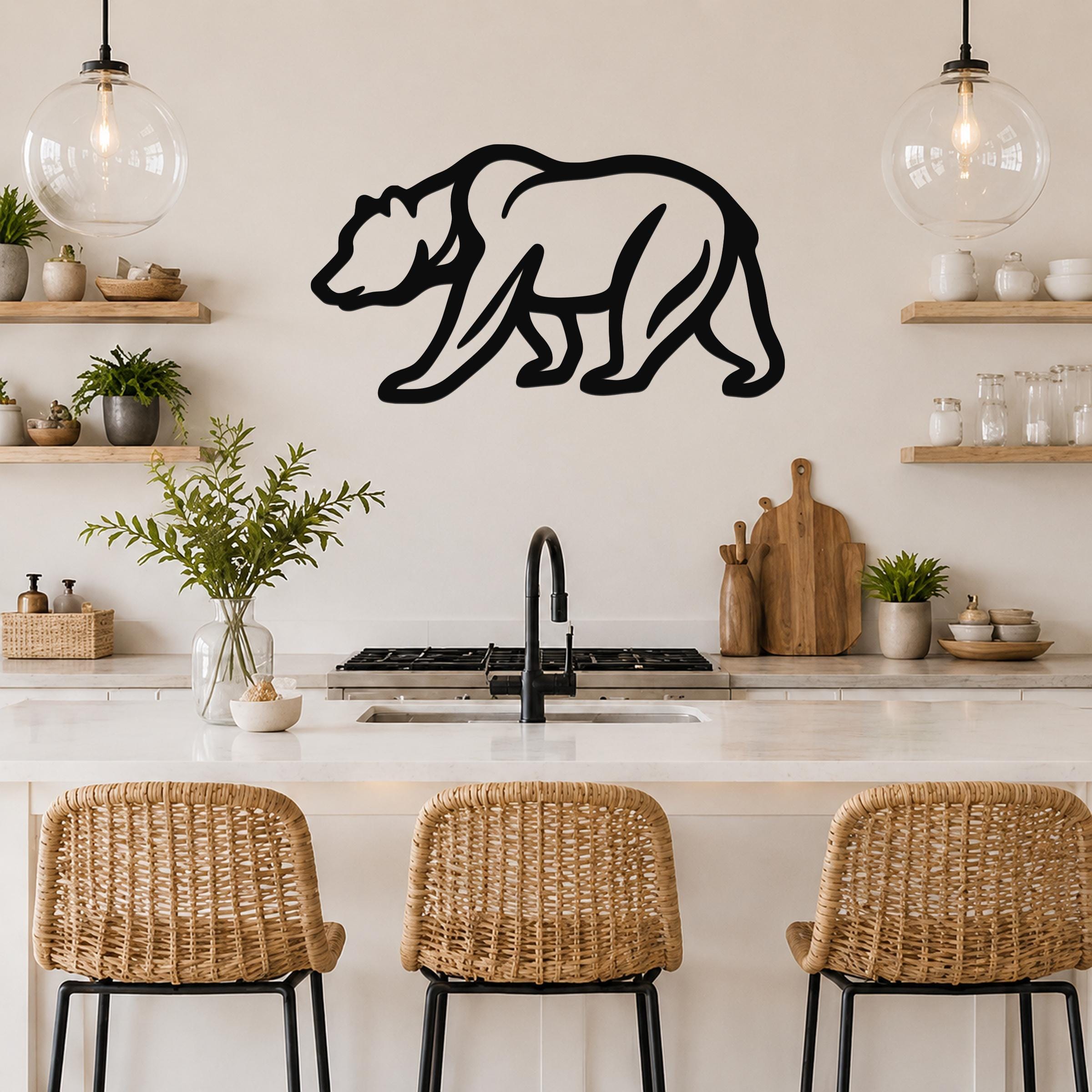 Black metal bear silhouette wall art with internal line details, mounted on a kitchen wall above a white countertop.