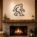 Black metal Bigfoot silhouette wall art mounted above a stone fireplace in a rustic living room.