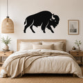 Black metal buffalo silhouette wall art mounted above a wooden bed in a neutral bedroom.