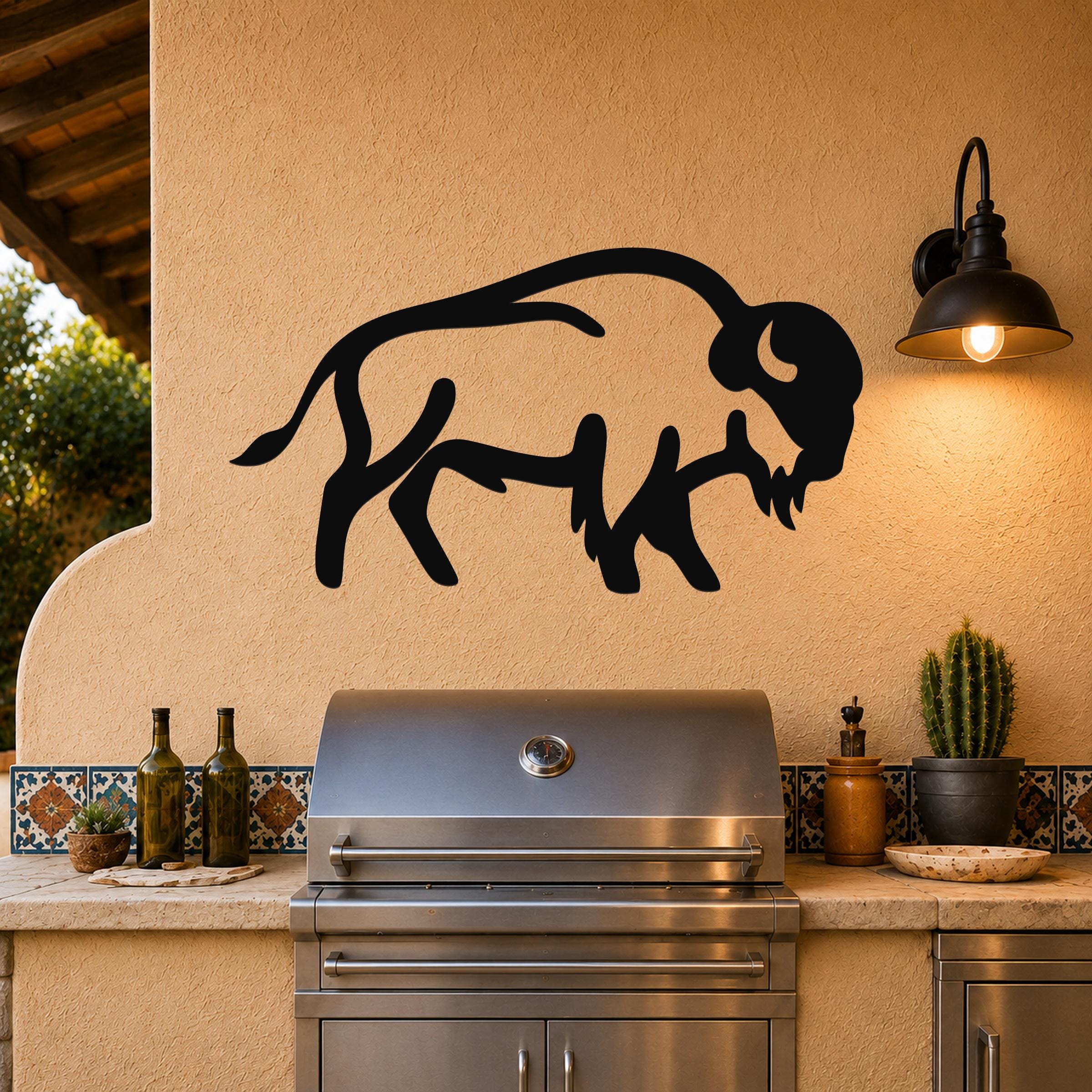 Black metal buffalo silhouette wall art mounted on a stucco wall above a stainless steel grill on an outdoor patio.