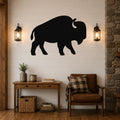 Black metal buffalo silhouette wall art mounted on a shiplap wall above a wooden console table in a rustic living room.