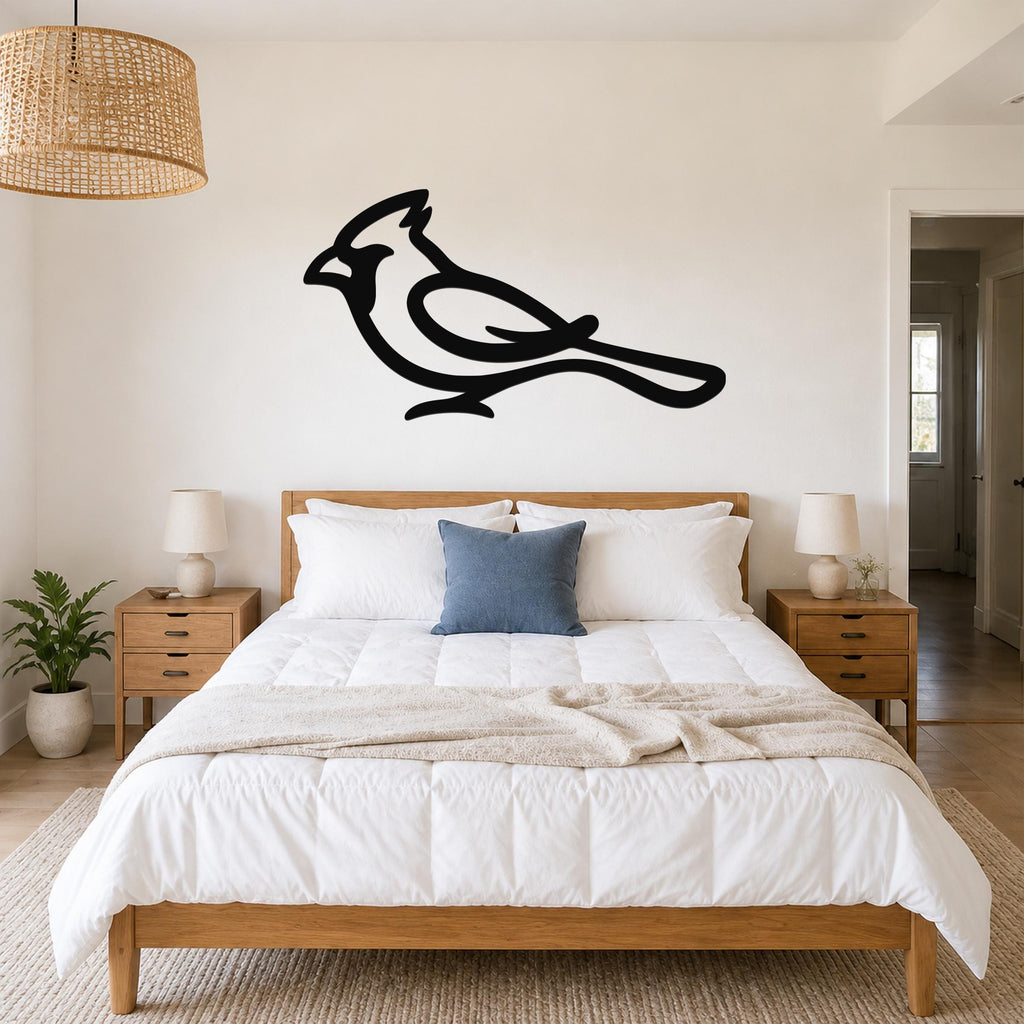 Black metal cardinal wall art in a bold silhouette style, mounted above a bed in a bright bedroom.